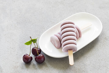 Cherry ice cream of spiral shape. On a wooden stick. On a plate. Close-up