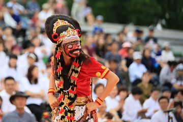 A person performing a mask dance performance in a traditional Indonesian costume