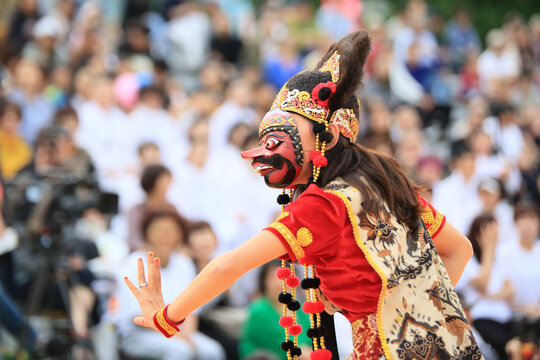 A person performing a mask dance performance in a traditional Indonesian costume