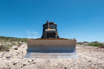 Bulldozer com lâmina frontal nivelando o solo para a construção de uma estrada