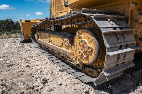 Parte lateral de um bulldozer com as suas lagartas e parte da lamina frontal na terraplanagem de terras