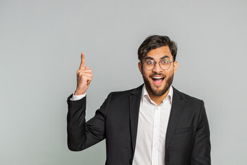 Eureka. Inspired Indian businessman pointing finger up with open mouth, having good idea, plan, startup, showing inspiration motivation gesture, problem solution. Arabian man on gray background