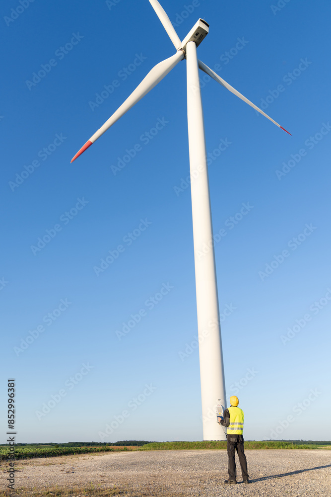 Poster engineer with digital tablet works on a field of wind turbines