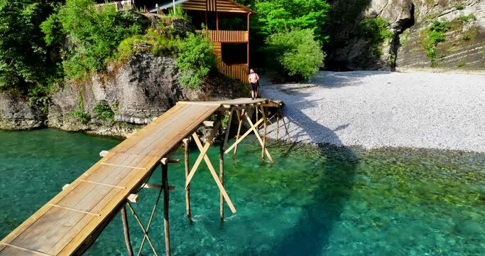 Young man taking photos over a wooden bridge over Shala River in Shkoder, northern Albania. 