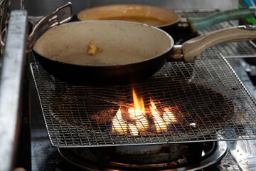 A pan with food on it is on a stove with a wire rack above it