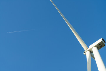 Wind turbine and plane in the blue sky