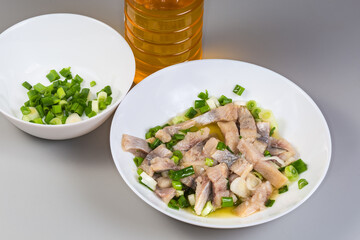 Sliced pickled atlantic herring with chopped green onion on dish