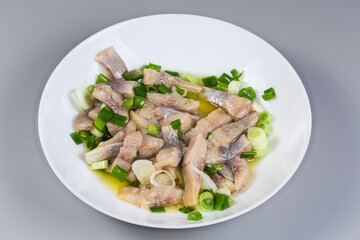 Sliced pickled atlantic herring with chopped green onion on dish