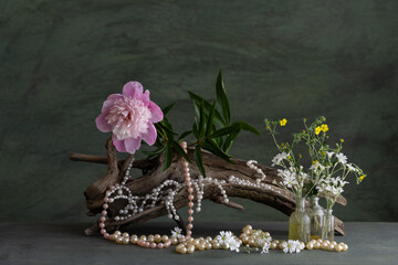a melancholic, romantic composition of pink peony flowers, with the use of a necklace, and tree...