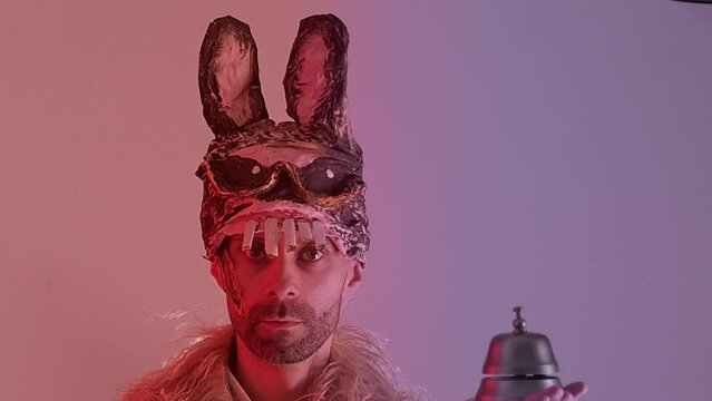 comic man, young guy in cringe in scary bunny mask smiles menacingly, rings ring, theme of fear and horror associated with mask and facial expression, Halloween and Festive Costumes