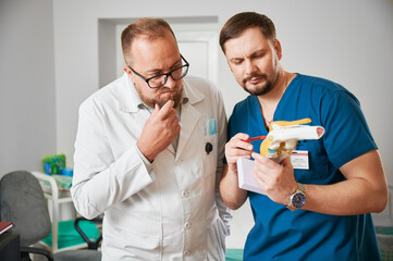Two doctors conducting consultation, thinking, deciding diagnose. Two man wearing uniform, working...