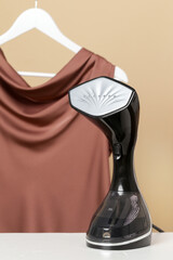 Upright garment steamer. Close up of vertical steamer with clothes ready for ironing. Concept of quick and easy ironing. 
