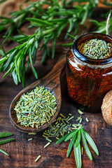 Rosemary in a wooden spoon. Dry and fresh fragrant rosemary, seasonings on a wooden board. Spices and herbs that are used for cooking meat and fish. Culinary concept.