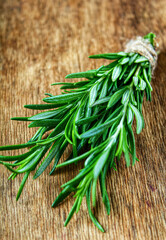 Rosemary on a wooden background. A bunch of fresh green fragrant rosemary. Spices and herbs, an ingredient for meat and fish. Culinary concept.