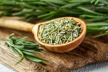 Rosemary in a wooden spoon. Dry and fresh fragrant rosemary, seasonings on a wooden board. Spices and herbs that are used for cooking meat and fish. Culinary concept.
