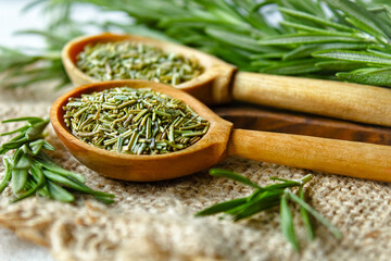 Rosemary in a wooden spoon. Dry and fresh fragrant rosemary, seasonings on a wooden board. Spices and herbs that are used for cooking meat and fish. Culinary concept.