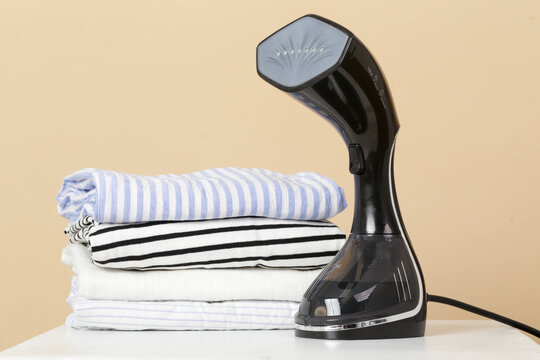 Upright garment steamer. Close up of vertical steamer with clothes ready for ironing. Concept of quick and easy ironing. 
