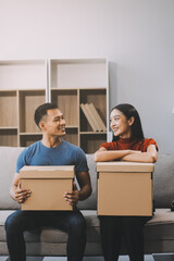 Young couple with big boxes moving into a new house, new apartment for couple, young man and woman helping to lift boxes and organize things for the new home, Moving house.