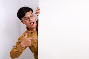 Portrait of young Indonesian civil servant happy excited positive smile point finger empty space billboard ad advice choice isolated over white background