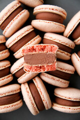 Texture inside of a macaron. French dessert macaron filled with dark chocolate ganache. Macarons are on a dark background. Top view. 