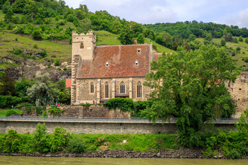 Medieval Church surrounded by lush forest seen while crusing the River Danube in Lower Austia