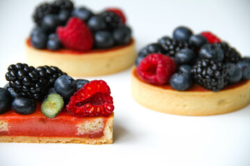 Texture inside of a tart. French dessert. Berry tart decorated with organic fresh blueberries, raspberries and blackberries. Back view. There is a copy space for your text.