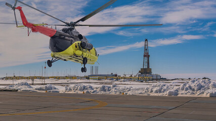 Collage. Yellow helicopter in the foreground. Drilling rig infrastructure on the Arctic oil and gas field in the background © vladend