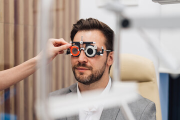 Attractive male doctor ophthalmologist is checking the eye vision of handsome middle age man in...