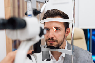 Attractive male doctor ophthalmologist is checking the eye vision of handsome middle age man in...