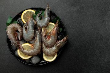 Large King prawns on lemon slices and ice. Black plate. Black background