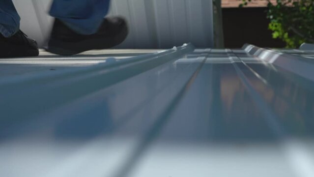 A workman installing steel roofing panels on a building