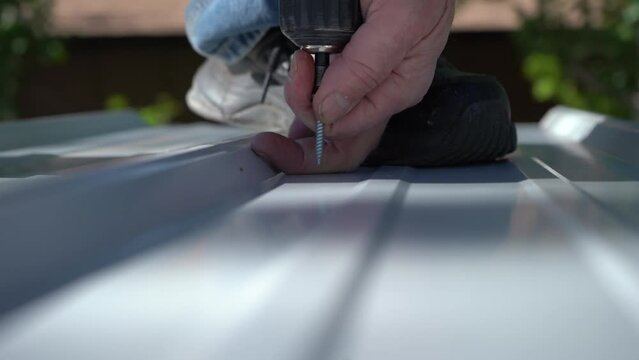 Close up of a man screwing down steel roofing on a building