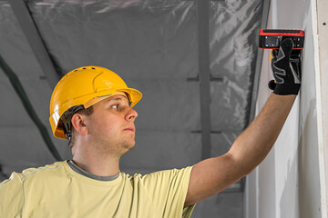 A construction worker is working with the laser distance meter.