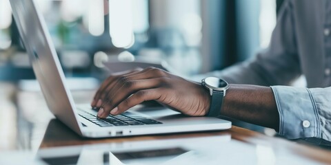 man's hands typing on a laptop keyboard in an office close up