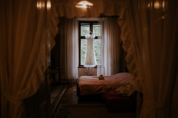 A beautifully captured wedding dress hanging in a room, showcasing its intricate design and elegance against a serene backdrop