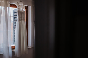 A beautifully captured wedding dress hanging in a room, showcasing its intricate design and elegance against a serene backdrop
