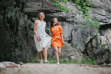 Naklejka premium Two young women in casual dresses enjoying a nature walk together near a rocky cliff, embracing joy and friendship.