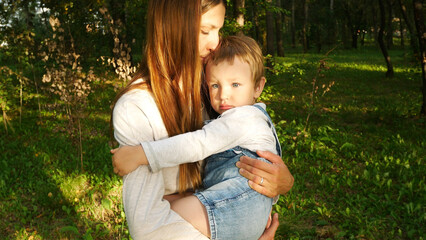 A young woman holding a cute child embracing in a green recreation area
