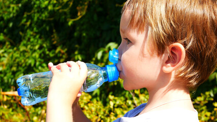 Close-up of a cute child drinking water from a plastic bottle