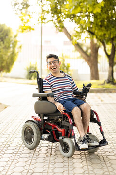 Vertical photo of a 40-year-old disabled adult man is sitting in an automatic wheelchair. The disabled man looks at the camera with joy.Concept of a man with cerebral palsy.
