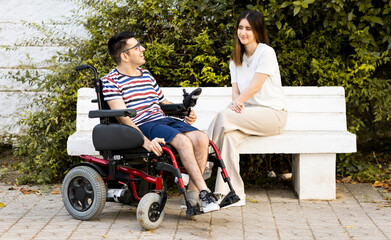 A 40-year-old disabled adult man sits in an automatic wheelchair next to a young woman.The woman...