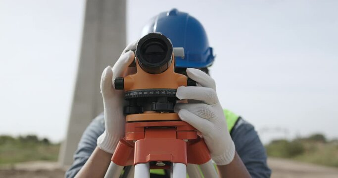 Civil engineer working with theodolite under a road construction bridge.  engineer surveyor is taking measurements with surveying instruments during a new road construction.