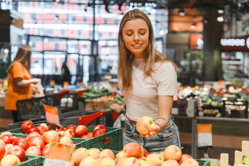 Young woman choosing apples in a grocery store. food concept