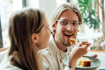Happy couple sharing cake and enjoying delicious dessert