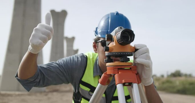 Civil engineer working with theodolite under a road construction bridge.  engineer surveyor is taking measurements with surveying instruments during a new road construction.