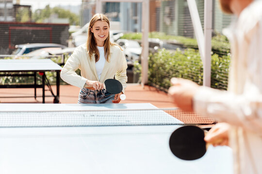 Young woman concentrating while playing ping pong outdoors, game concept - Powered by Adobe