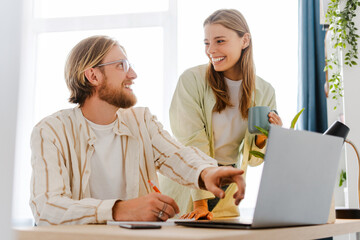 Young happy couple using laptop and smiling while working from home office