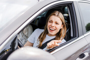Naklejka premium Angry young woman driver shouting at another driver while driving a car