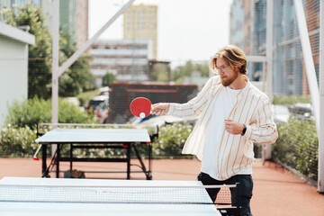 Young man playing ping pong outdoors in the city, sport, game concept