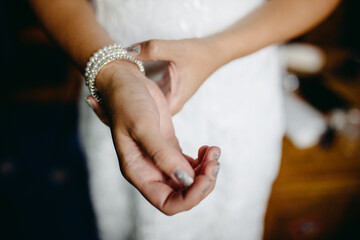 A detailed close-up of a bride adjusting a delicate wrist corsage, capturing the intricate details...